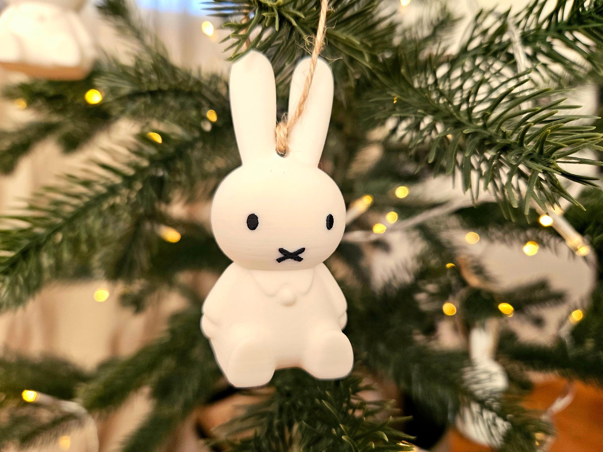 White rabbit ornament hanging on a Christmas tree with blurred lights in the background