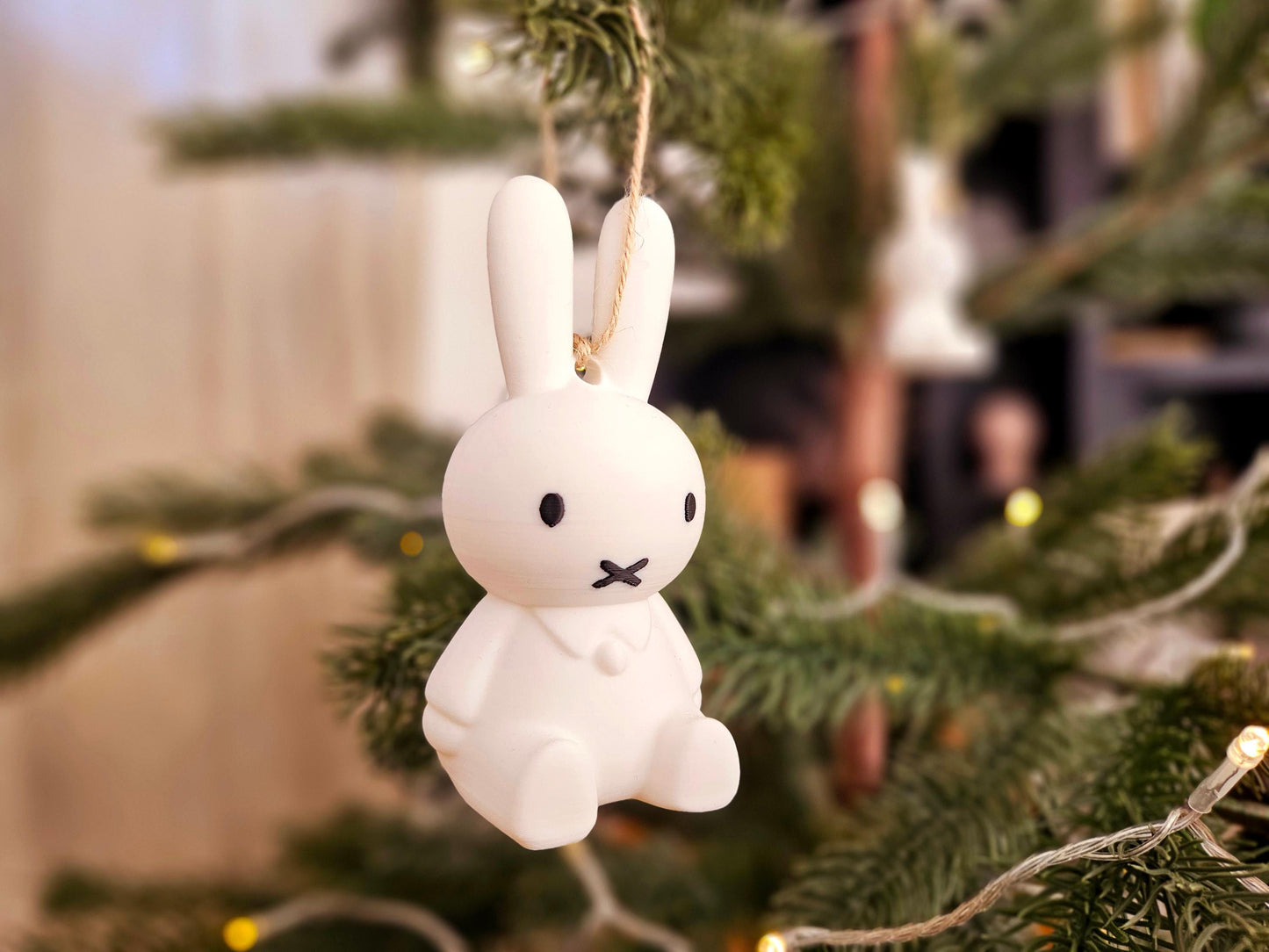 White rabbit ornament hanging on a Christmas tree with blurred background